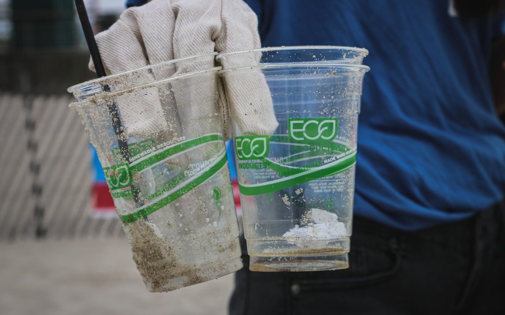 Un agent d'assainissement tenant des tasses à café en plastique vides.