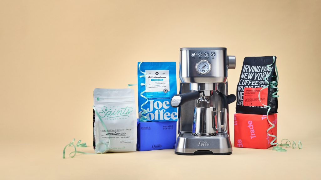 Une machine à espresso domestique à côté de sacs de café torréfié.