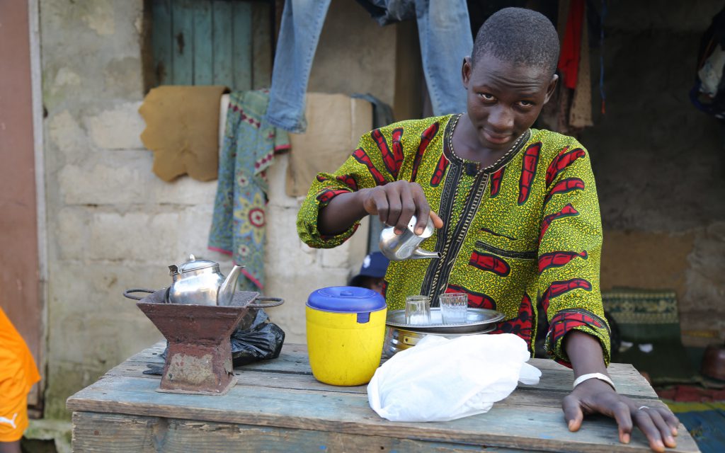 Un homme prépare du café sur le bord de la route en Guinée.