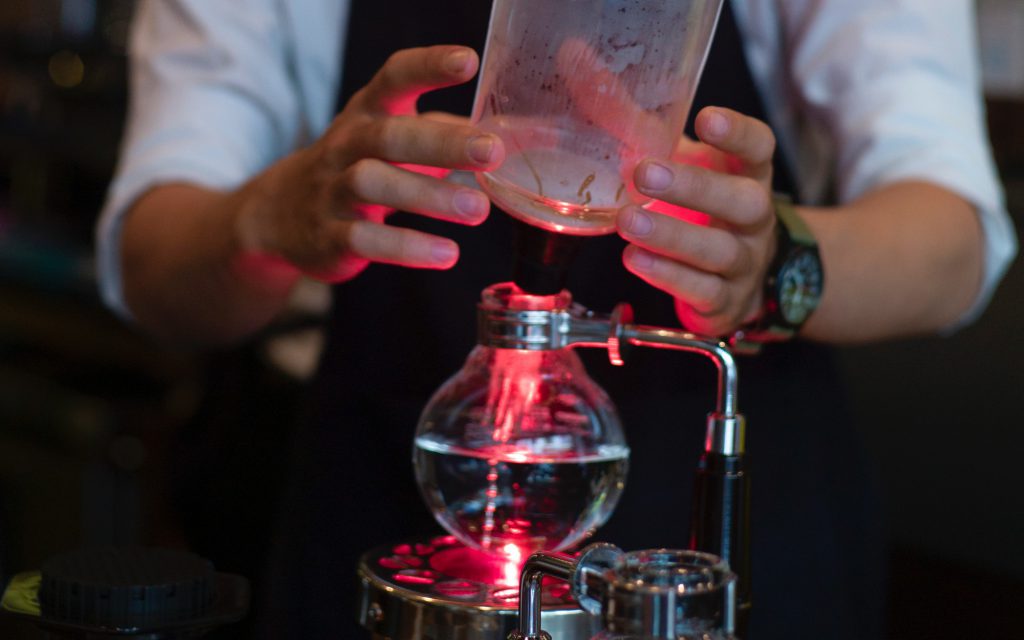 Un barista prépare un brasseur à siphon.