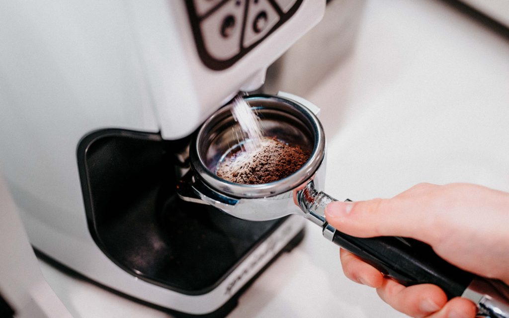 Un barista moud du café dans un portafiltre.