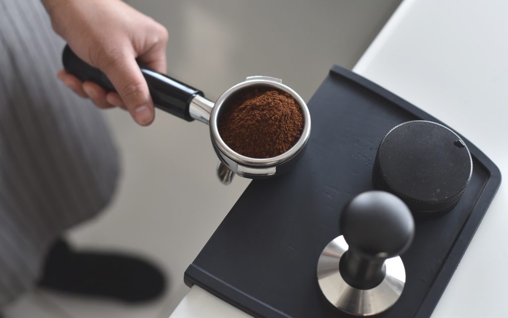 Un barista se prépare à distribuer et à tasser le café moulu dans un portafiltre.